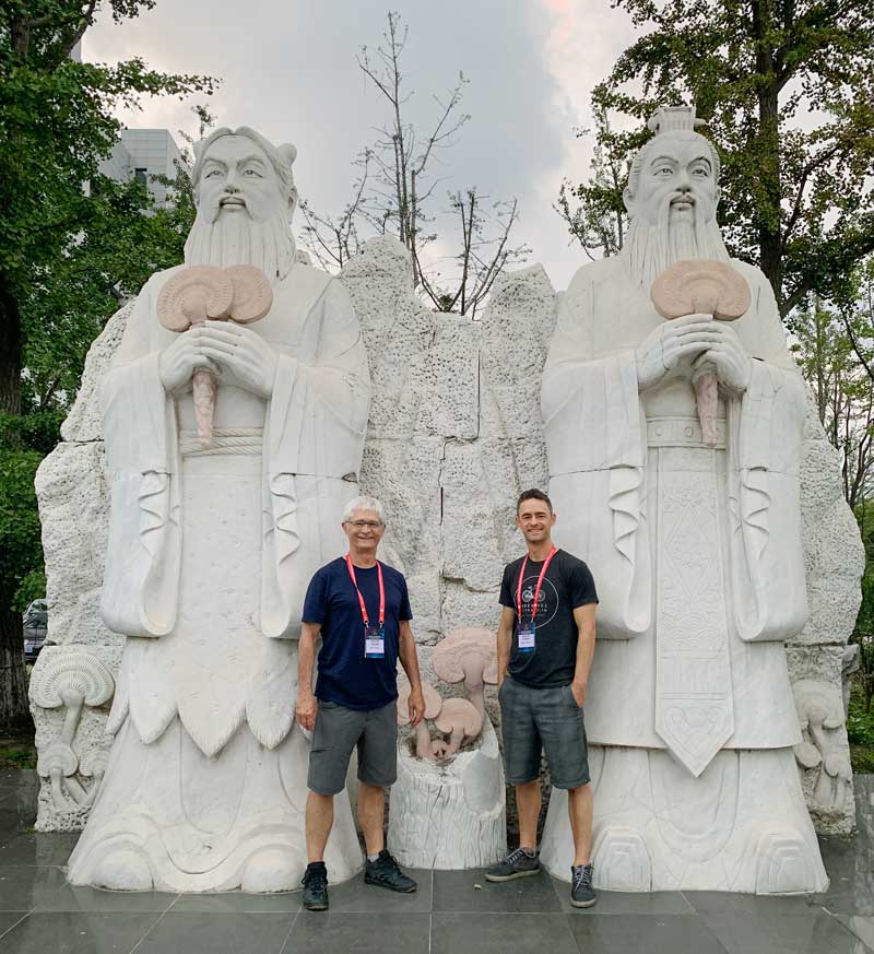 Jeff and Skye Chilton in front of a pair of Reishi statues in China.